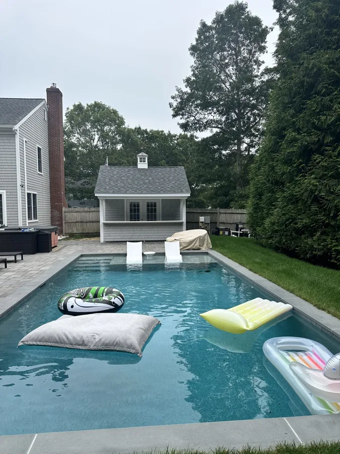 Pool with floats beside a Cape Cod pool house