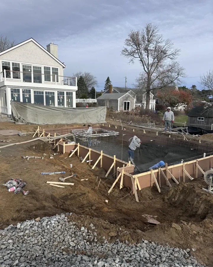 Crew pouring concrete for a new pool construction project